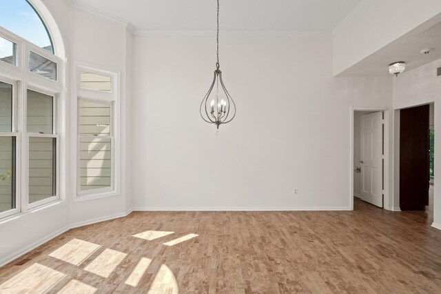 unfurnished room featuring a notable chandelier, crown molding, and wood-type flooring