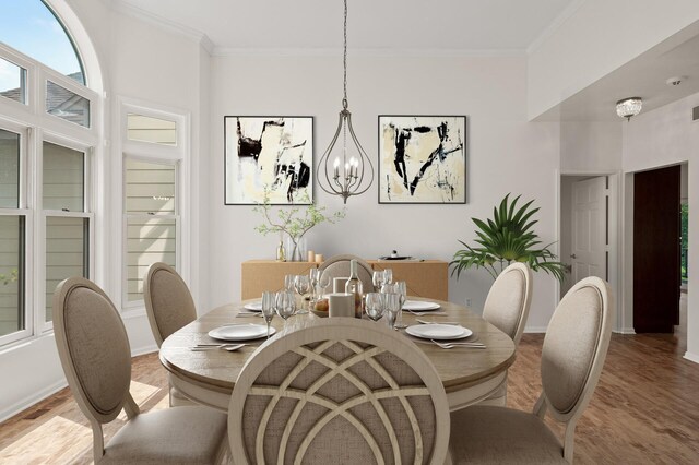 dining space with an inviting chandelier, crown molding, and wood-type flooring