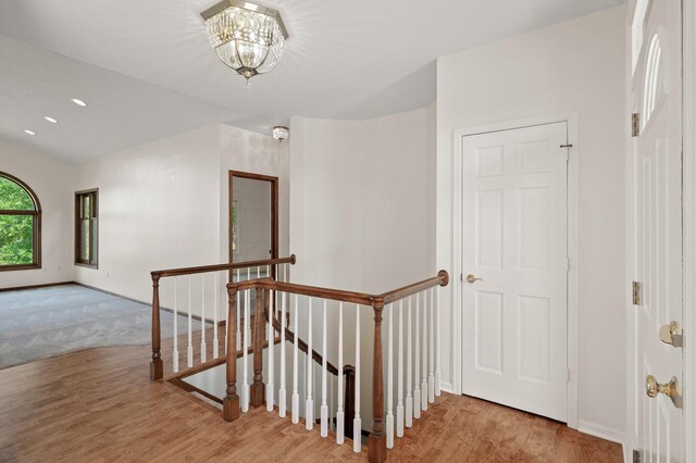 corridor with an inviting chandelier and light hardwood / wood-style flooring