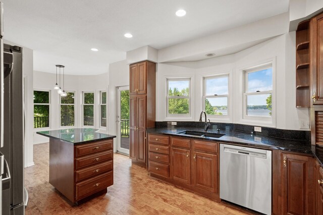 kitchen with dark stone counters, a center island, sink, appliances with stainless steel finishes, and light hardwood / wood-style floors