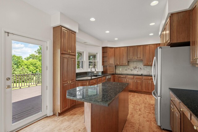 kitchen with dark stone counters, sink, light hardwood / wood-style floors, tasteful backsplash, and fridge