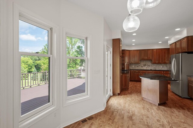 kitchen featuring light hardwood / wood-style flooring, decorative light fixtures, tasteful backsplash, stainless steel refrigerator, and a kitchen island