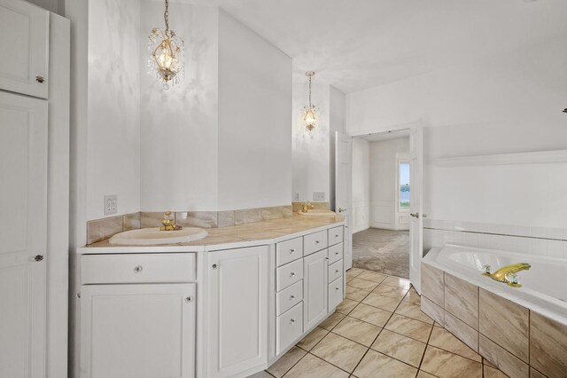 bathroom with tiled bath, vanity, and tile patterned floors