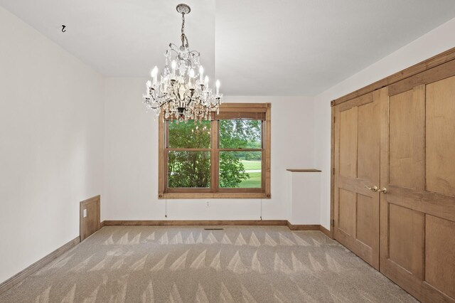 unfurnished bedroom featuring a closet, a chandelier, and light colored carpet