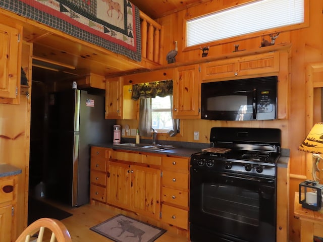 kitchen with sink, wood walls, and black appliances