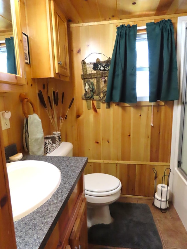 bathroom with tile patterned floors, vanity, wood walls, and toilet