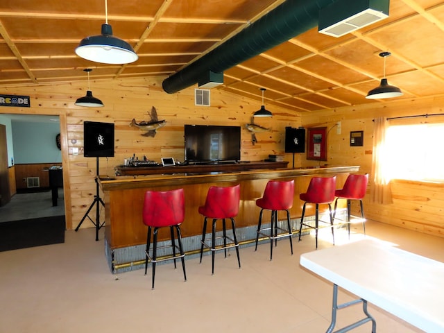 bar with pendant lighting, concrete floors, wooden walls, and vaulted ceiling