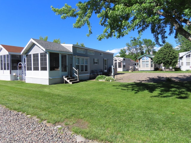 rear view of house featuring a sunroom and a yard