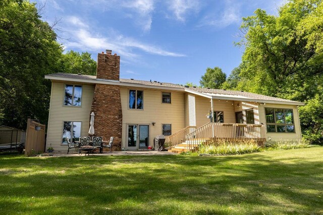 rear view of property featuring a yard, a chimney, and a patio