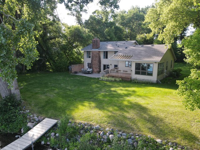 back of house featuring a deck, a lawn, a pergola, a chimney, and a patio area