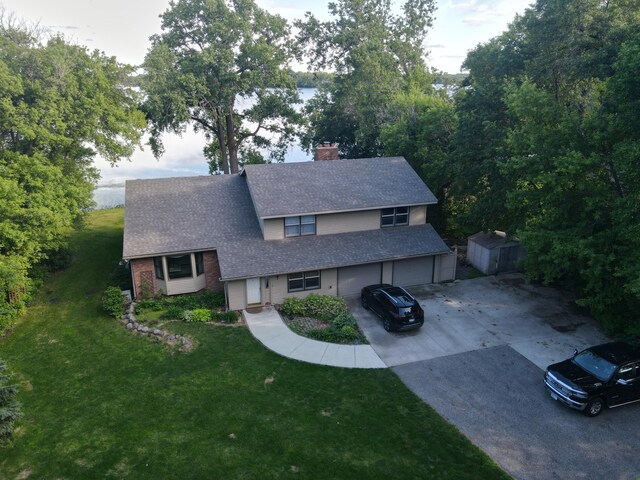 view of front of house with a shingled roof, a chimney, a storage unit, an outdoor structure, and a front lawn