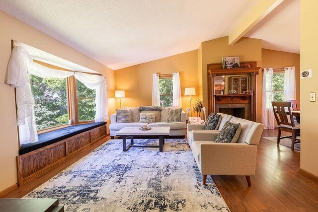 living area featuring a wealth of natural light, lofted ceiling with beams, and wood finished floors