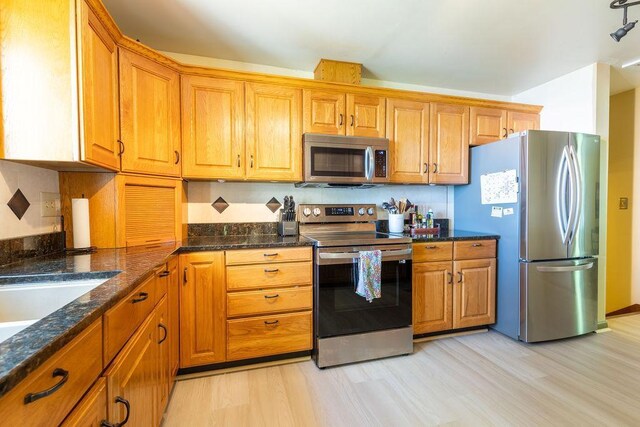 kitchen with stainless steel appliances, brown cabinets, and light wood-style floors