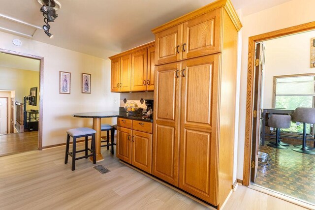 kitchen featuring light wood-style flooring, baseboards, and brown cabinets