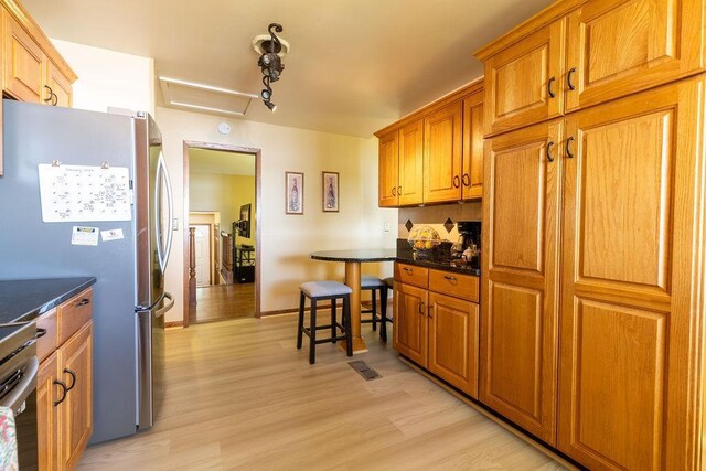 kitchen featuring light wood-style floors, visible vents, brown cabinetry, and freestanding refrigerator