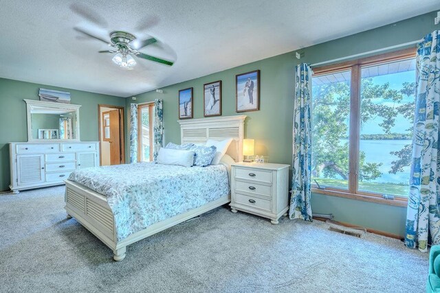 bedroom with light carpet, ceiling fan, visible vents, and a textured ceiling