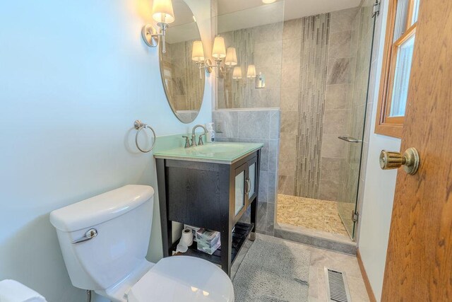 full bathroom with toilet, a notable chandelier, vanity, visible vents, and a tile shower