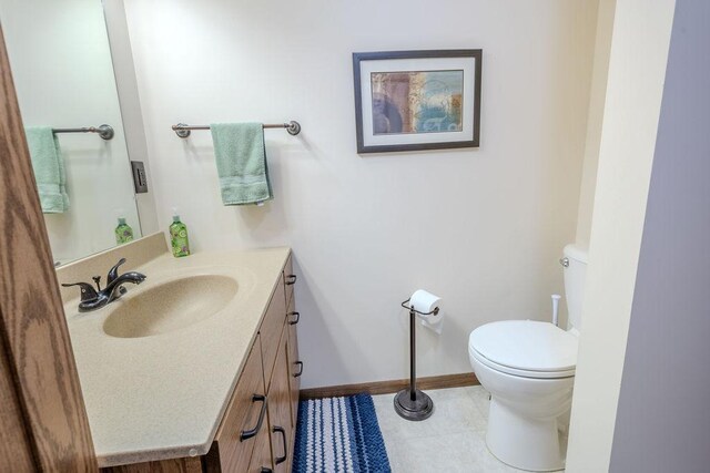 bathroom with toilet, tile patterned flooring, vanity, and baseboards