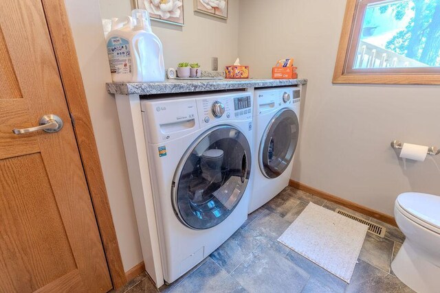 clothes washing area featuring laundry area, baseboards, visible vents, independent washer and dryer, and stone tile flooring