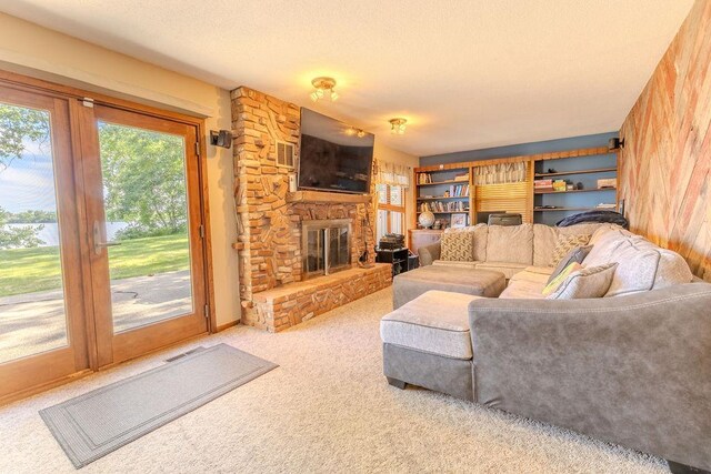 living area featuring a textured ceiling, a stone fireplace, visible vents, and light colored carpet