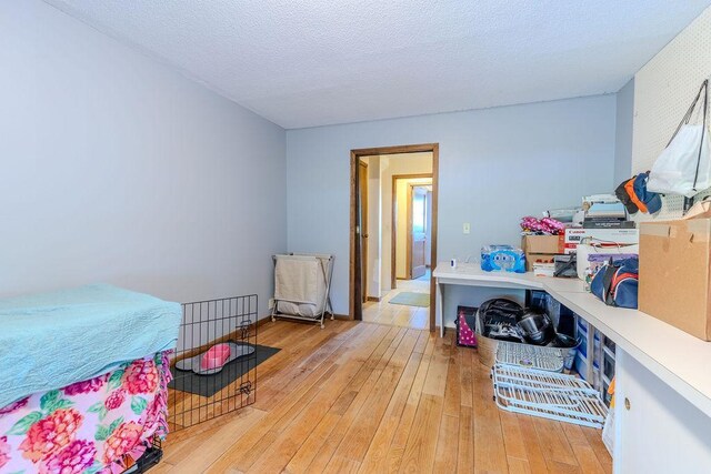 bedroom with light wood-type flooring and a textured ceiling