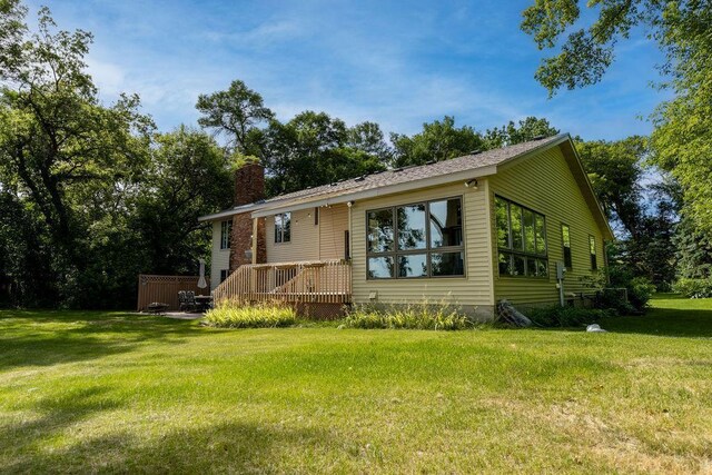 view of front facade with a deck, a chimney, and a front lawn