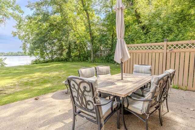 view of patio with a water view, fence, and outdoor dining space