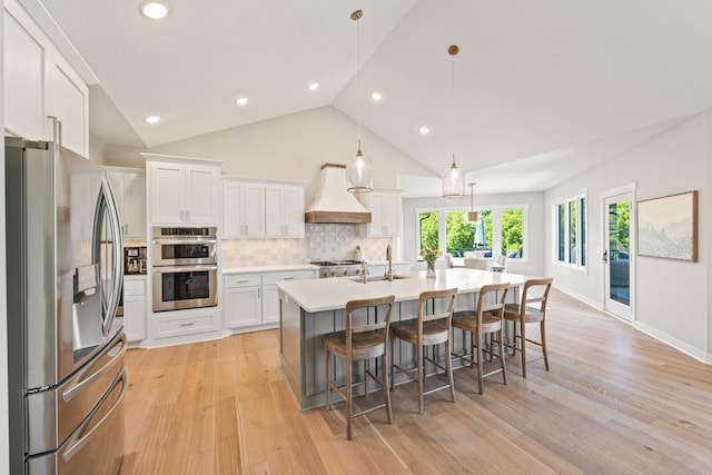 kitchen featuring custom exhaust hood, backsplash, white cabinets, hanging light fixtures, and stainless steel appliances