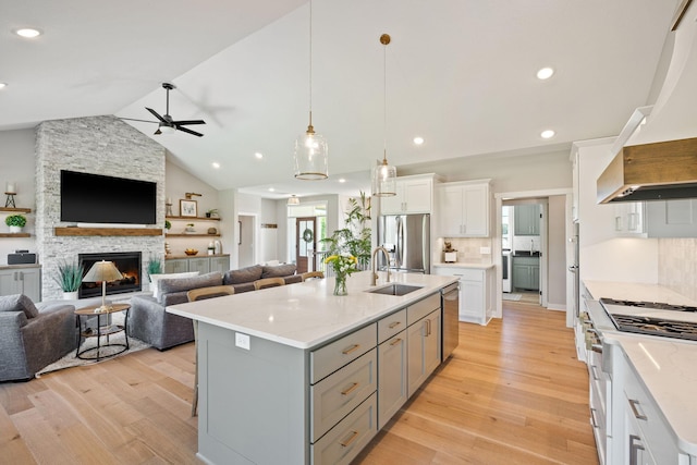 kitchen featuring white cabinetry, hanging light fixtures, sink, custom range hood, and appliances with stainless steel finishes