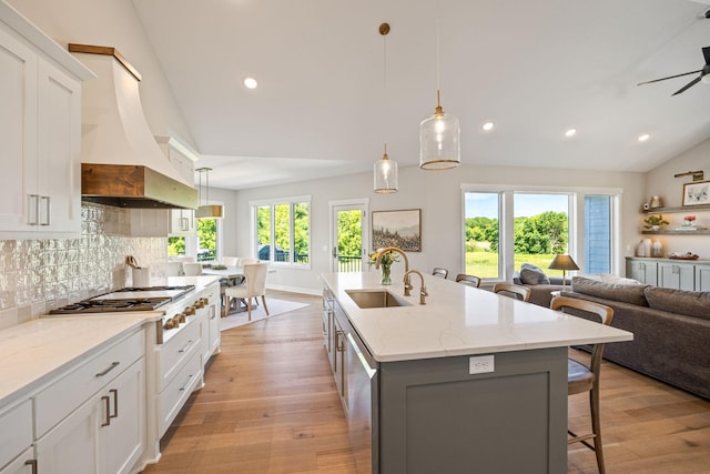 kitchen with white cabinets, an island with sink, sink, and hanging light fixtures