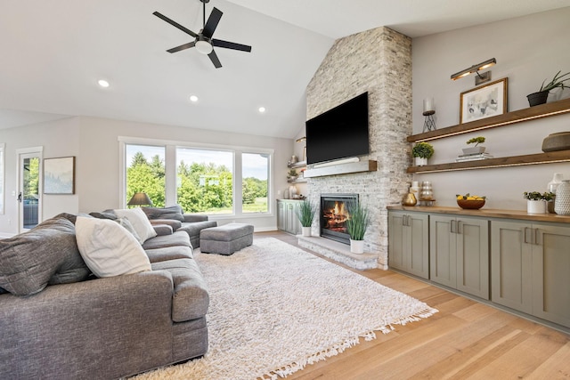 living room featuring a fireplace, light hardwood / wood-style flooring, high vaulted ceiling, and ceiling fan