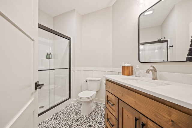 bathroom with toilet, vanity, and a shower with door