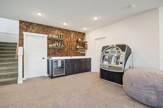 bar with light colored carpet, sink, dark brown cabinetry, and beverage cooler