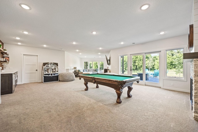 recreation room featuring a textured ceiling, pool table, and light colored carpet