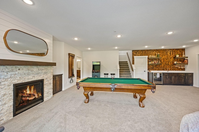 playroom with light carpet, billiards, indoor bar, and a stone fireplace