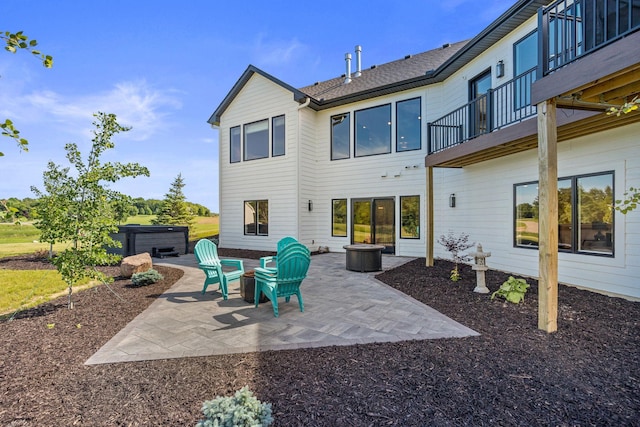 rear view of house with a patio, a balcony, and a hot tub