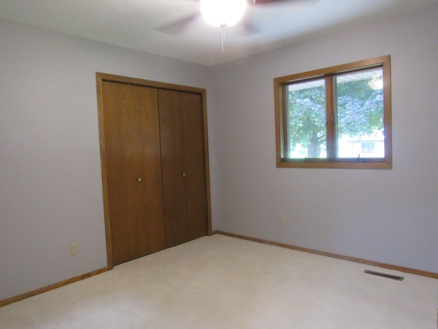 unfurnished bedroom with ceiling fan, a closet, and carpet