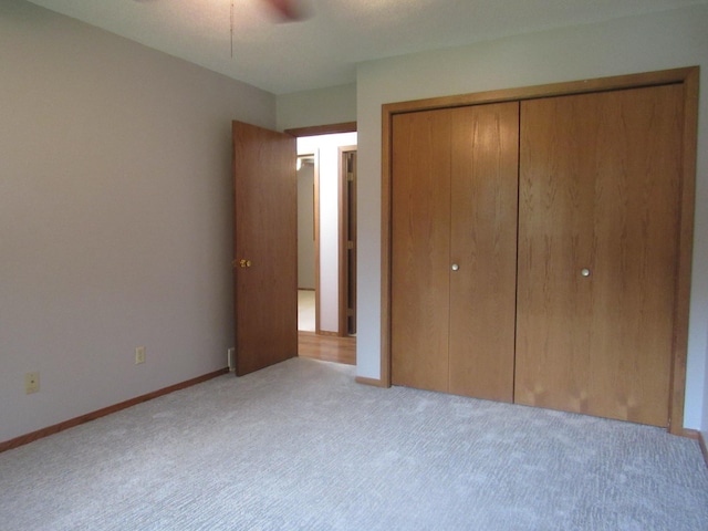 unfurnished bedroom with ceiling fan, a closet, and light colored carpet