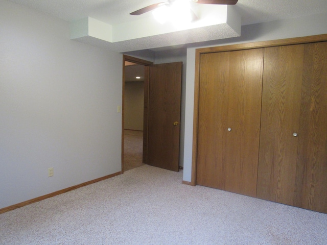 unfurnished bedroom featuring light carpet, a closet, and ceiling fan