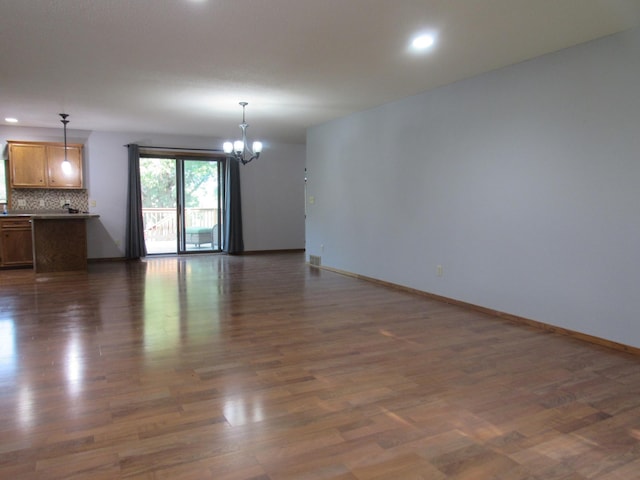 unfurnished living room featuring dark hardwood / wood-style flooring and a notable chandelier