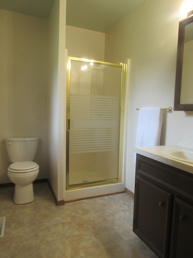 bathroom with vanity, toilet, and a shower with door