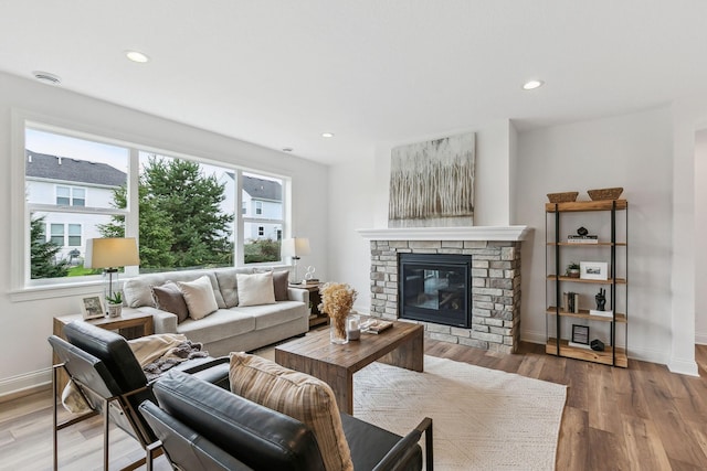 living room with light wood-type flooring and a stone fireplace