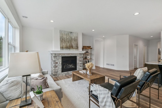 living room with a wealth of natural light, a stone fireplace, and light wood-type flooring