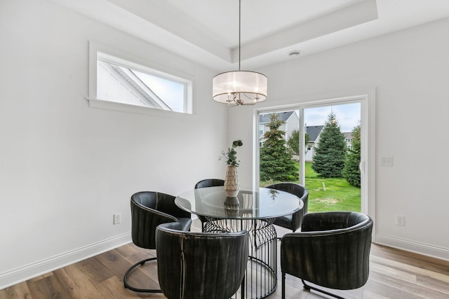 dining area featuring hardwood / wood-style floors, a raised ceiling, and a notable chandelier