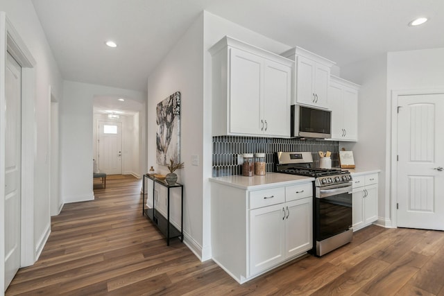 kitchen with white cabinets, appliances with stainless steel finishes, dark hardwood / wood-style flooring, and decorative backsplash