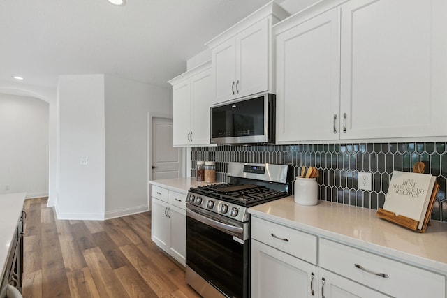 kitchen with stainless steel appliances, wood-type flooring, white cabinets, and tasteful backsplash