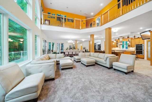 living room featuring a towering ceiling, light tile patterned flooring, ornate columns, and a chandelier