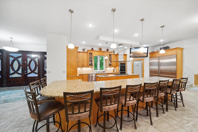 kitchen featuring appliances with stainless steel finishes, a large island, island range hood, and pendant lighting