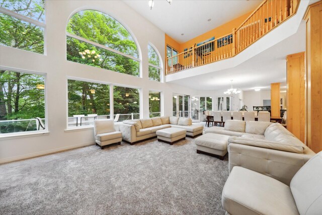 carpeted living room featuring a notable chandelier, a wealth of natural light, and a high ceiling