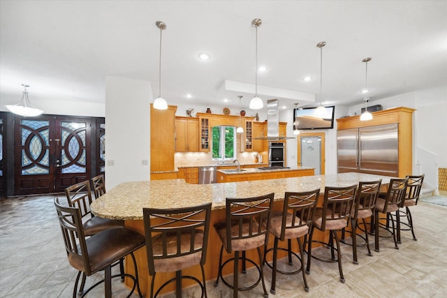 kitchen featuring island range hood, pendant lighting, appliances with stainless steel finishes, and a spacious island